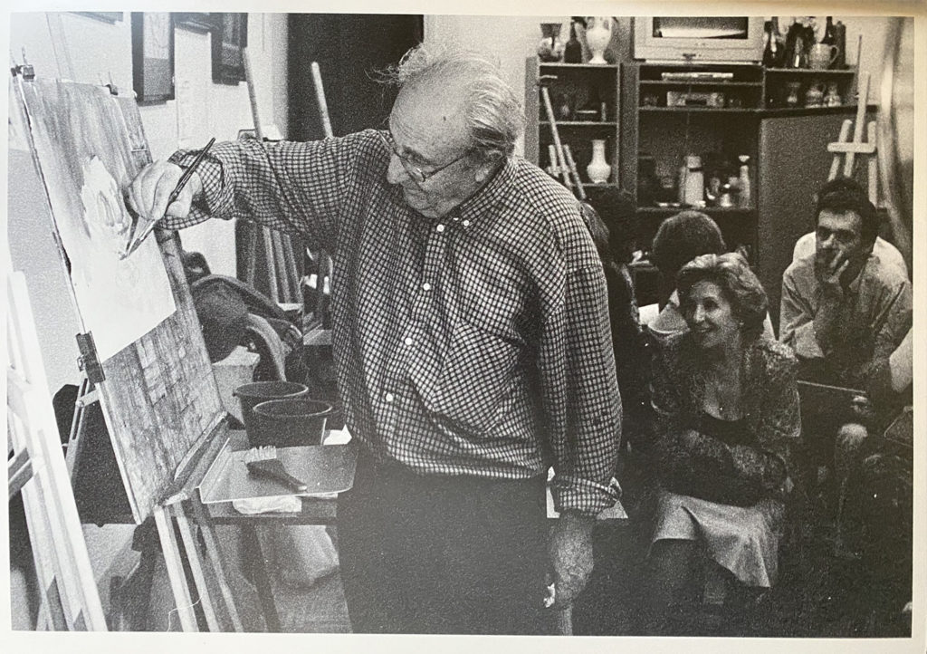 Luis Borruel painting at the easel while seated onlookers watch