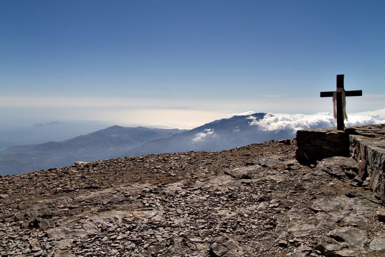 A wooden cross on the stony summit of Psiloritis, cloud lying over the ranges and the hazy sea far below