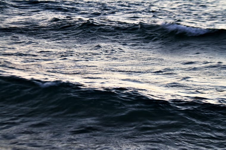 Low evening light catching the ridges of a dark, restless sea